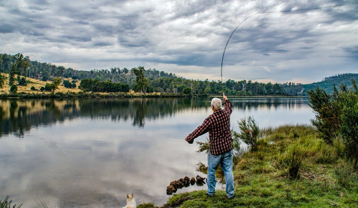 Mand fisker i sø med fiskestang